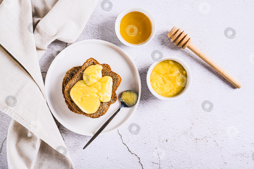 Скачать Утренние бутерброды на зерновом хлебе с медом и сливочным маслом на тарелке на столе вид сверху фотосток Ozero