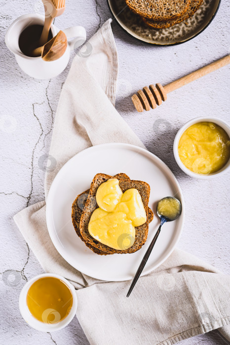 Скачать Вкусные тосты с медовым маслом на тарелке, стоящей на столе вертикально фотосток Ozero