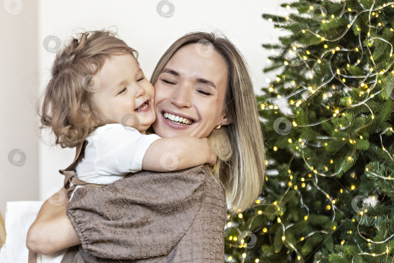 Скачать Молодая женщина со светлыми волосами и маленькой дочерью на фоне рождественских украшений. Концепция нового года фотосток Ozero