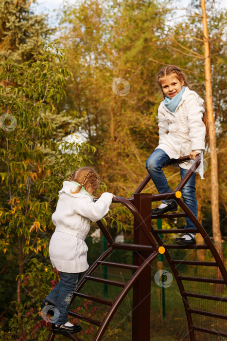 Скачать Сестры взбираются по лестнице на детскую площадку. фотосток Ozero