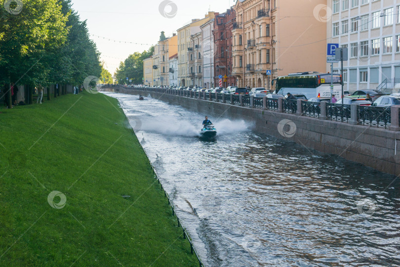 Скачать мужчина катается на гидроцикле по каналу в городе фотосток Ozero