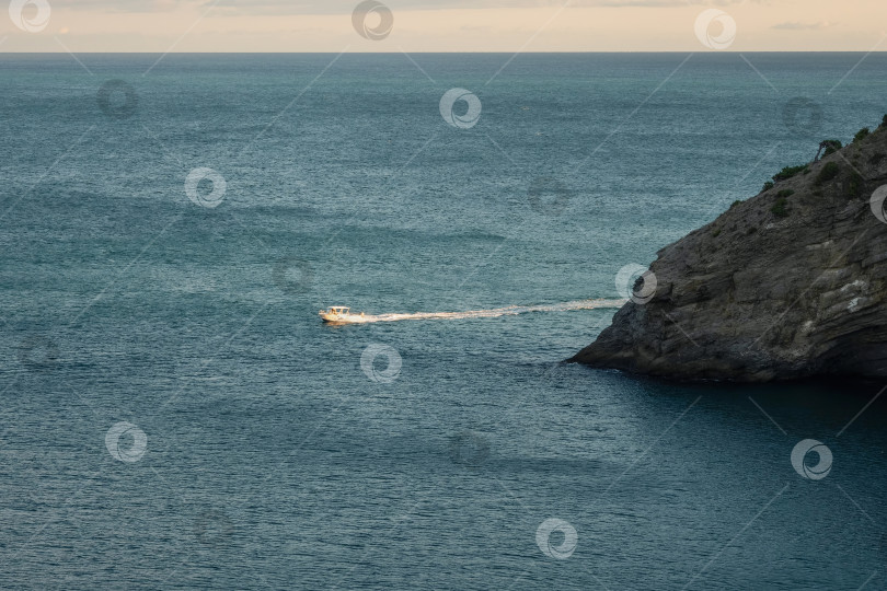 Скачать Побережье Черного моря. Маленькая лодка в море у скалистого обрыва. фотосток Ozero