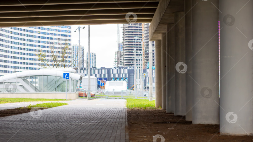 Скачать Человек неторопливо прогуливается по тротуару под мостом фотосток Ozero