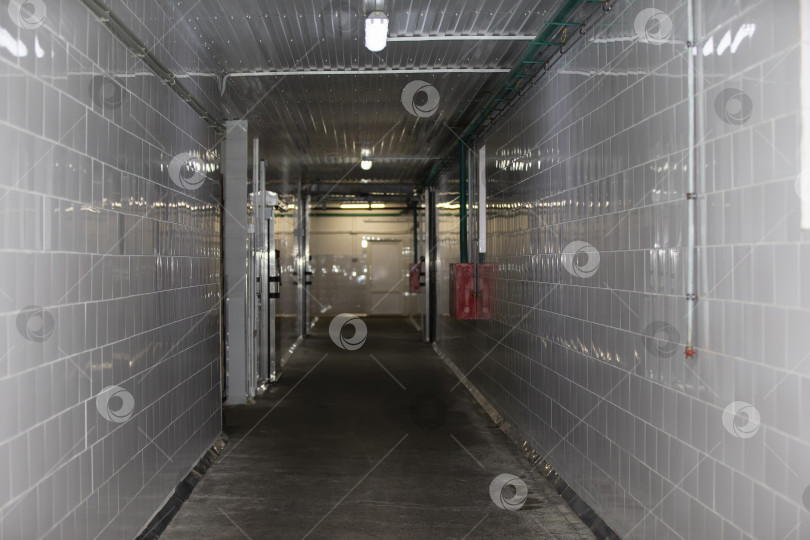 Скачать Пустой коридор фабрики или цеха облицован плиткой, а пол - бетоном. фотосток Ozero