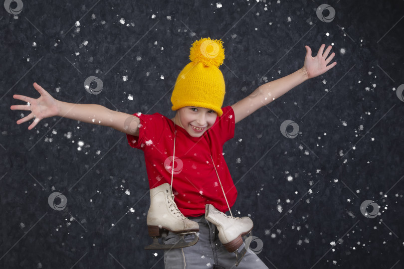 Скачать Красивый маленький мальчик в вязаной желтой шапочке и винтажных коньках на сером фоне. фотосток Ozero