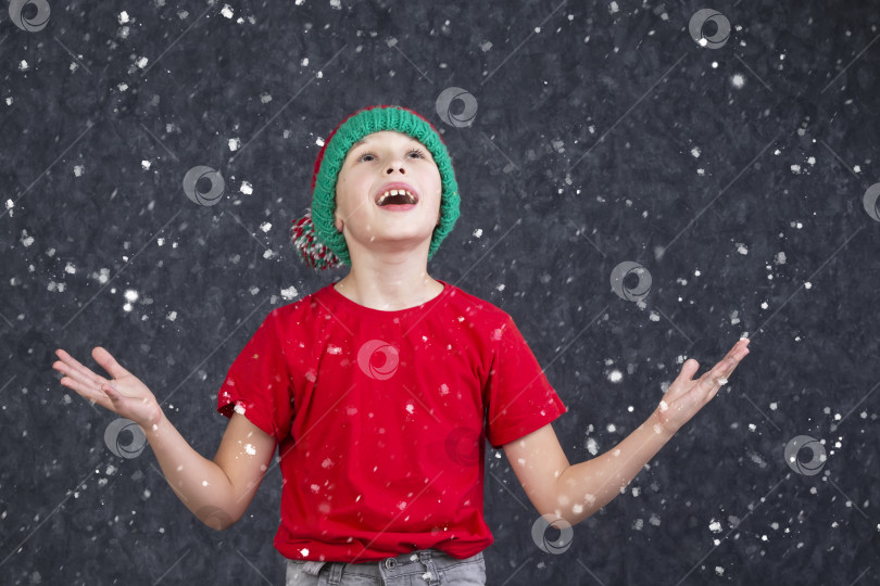 Скачать Забавный маленький мальчик в красной футболке ловит летящий снег. фотосток Ozero