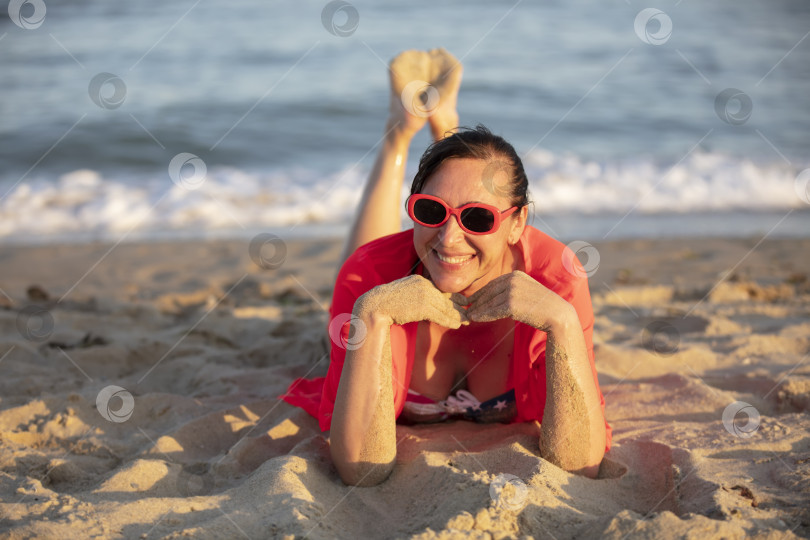 Скачать Счастливая женщина средних лет на побережье смотрит в камеру и улыбается. фотосток Ozero