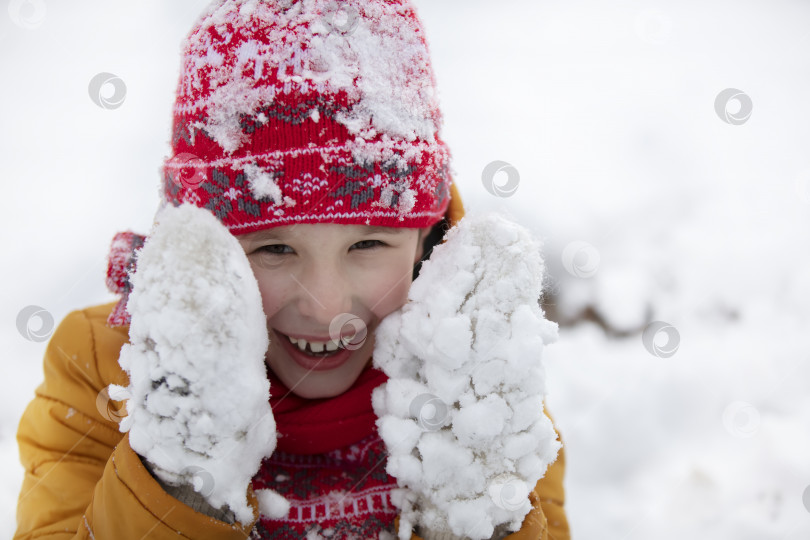 Скачать Счастливый маленький мальчик зимой в заснеженных варежках. фотосток Ozero