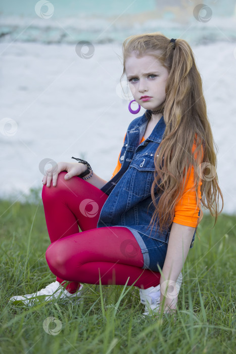 Скачать Портрет маленькой рыжеволосой девочки с ярким макияжем, в джинсовой жилетке и красных леггинсах. фотосток Ozero