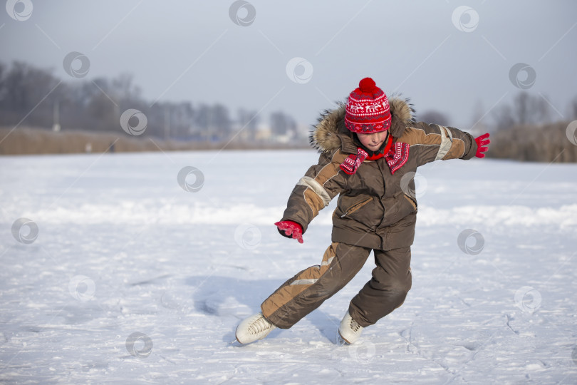 Скачать Ребенок на льду зимой. Мальчик катается на коньках по ледяному озеру. фотосток Ozero