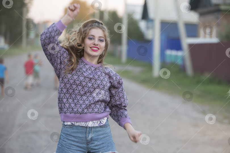 Скачать Счастливая молодая девушка танцует на улице.Красивая девушка с длинными волосами подняла руку вверх. фотосток Ozero