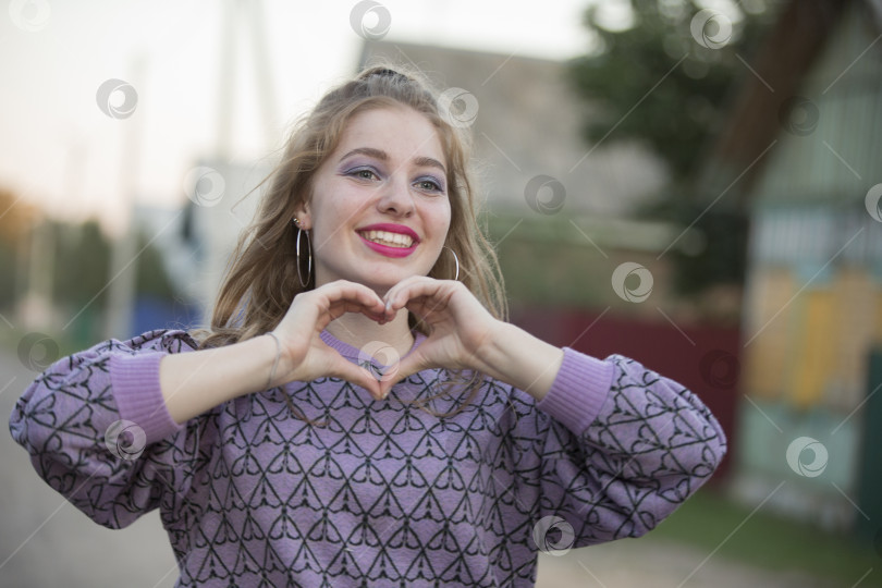 Скачать Счастливая молодая девушка показывает пальцами знак сердца. фотосток Ozero