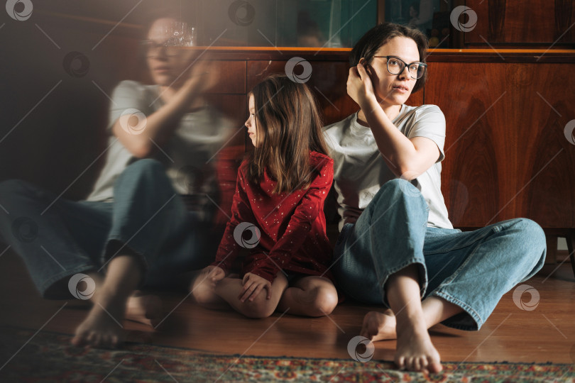 Скачать Девочка-подросток и ее мать сидят на полу в гостиной дома, ребенок смотрит на отражение фотосток Ozero