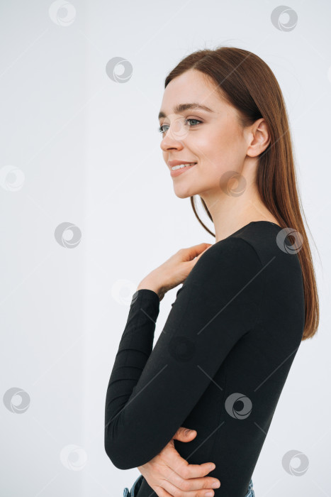 Скачать Вертикальный портрет счастливой молодой красивой женщины с темными длинными волосами в черном лонгсливе и джинсах на белом фоне изолированно фотосток Ozero