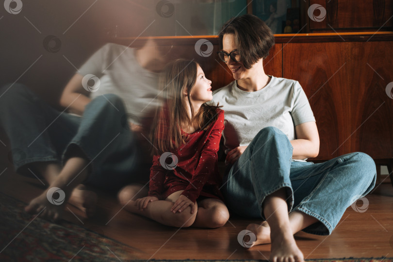 Скачать Девочка-подросток и ее мать сидят на полу в гостиной дома фотосток Ozero