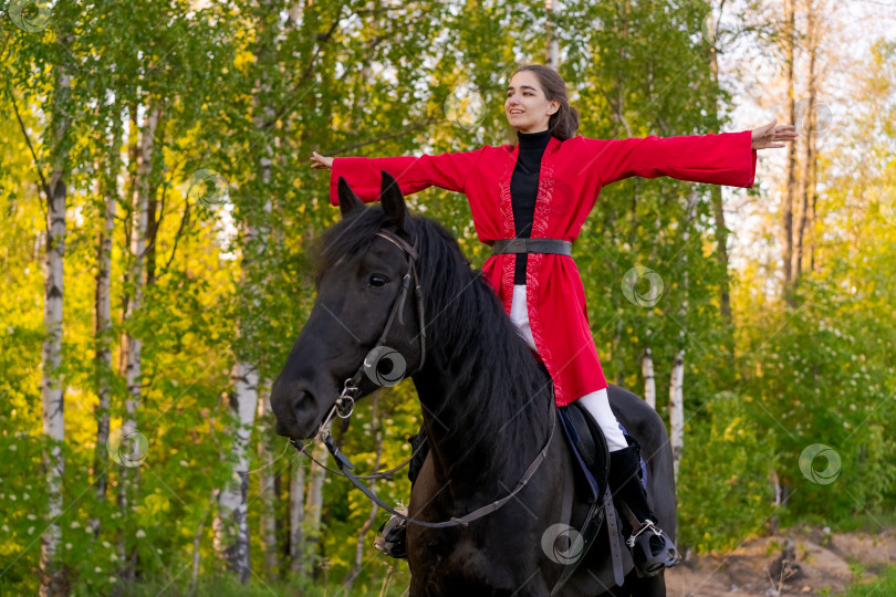 Скачать Женщина едет верхом на черном коне по лесу фотосток Ozero