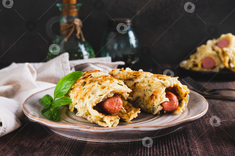 Скачать Блинчики с сосисками, завернутые в нашинкованную капусту, на тарелке на столе фотосток Ozero