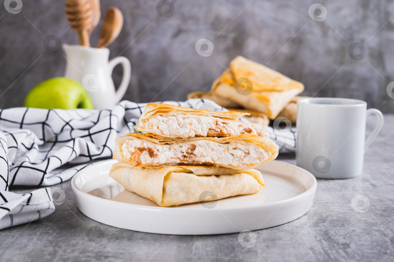 Скачать Аппетитные конвертики с творогом и яблоком в лаваше на тарелке на столе фотосток Ozero