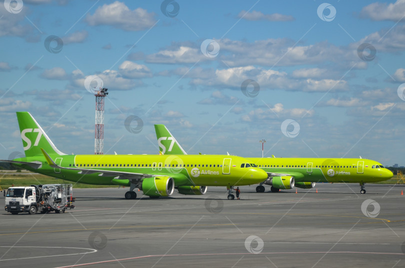 Скачать Зеленый самолет S7 Airlines на фоне голубого неба. Пассажирский авиалайнер Boeing 737-800 находится на взлетно-посадочной полосе фотосток Ozero