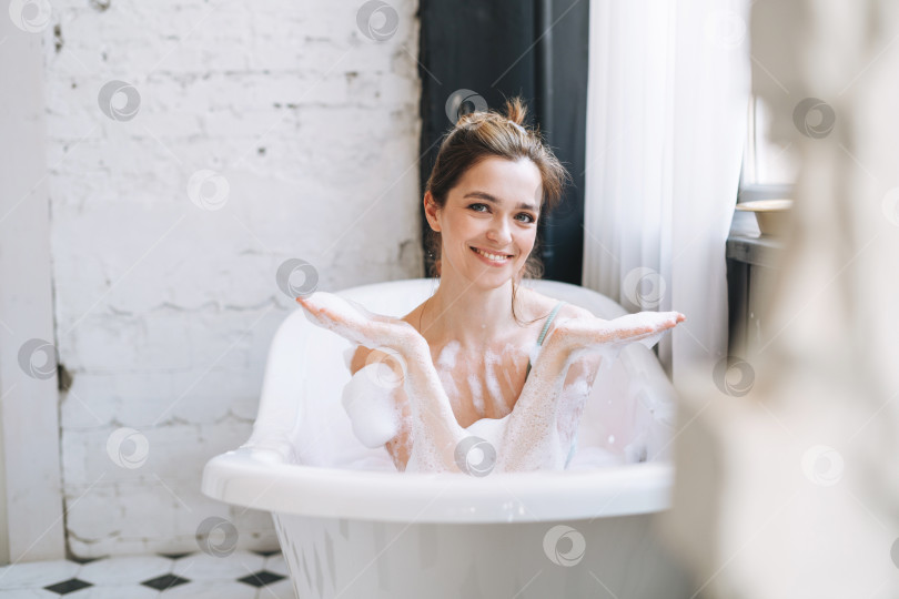 Скачать Молодая счастливая женщина, принимающая ванну с пеной дома, побалуйте себя фотосток Ozero