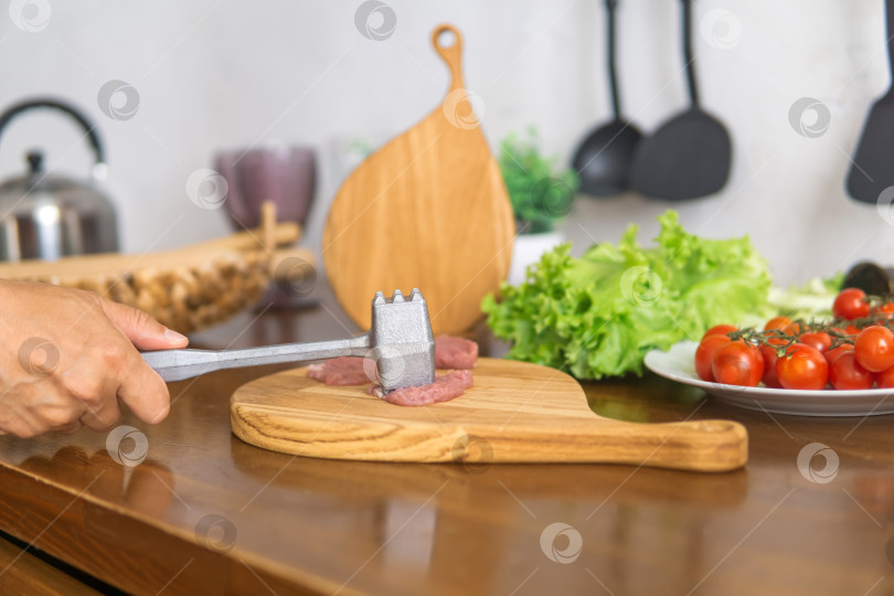 Скачать человек отбивает мясо с помощью устройства для размягчения мяса фотосток Ozero