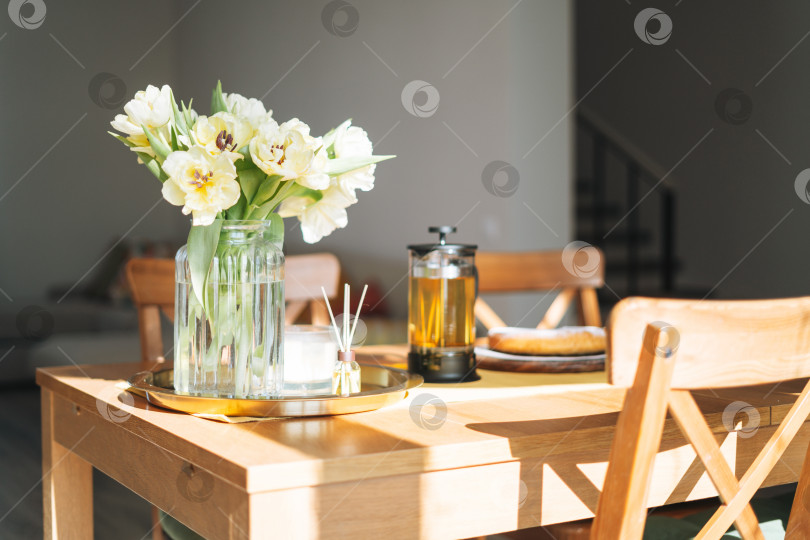Скачать Красивый букет желтых тюльпанов в вазе на обеденном столе в белой кухне светлый интерьер дома фотосток Ozero