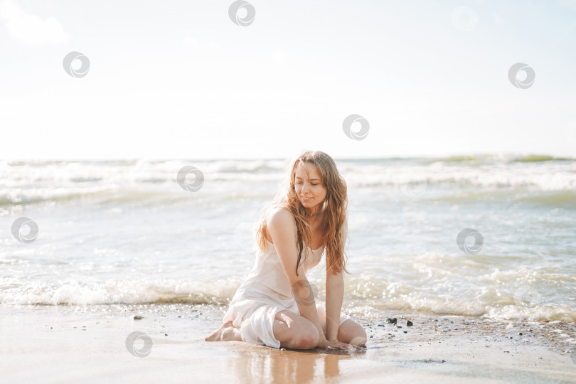 Скачать Молодая красивая блондинка с длинными волосами в белом платье наслаждается жизнью на морском пляже фотосток Ozero