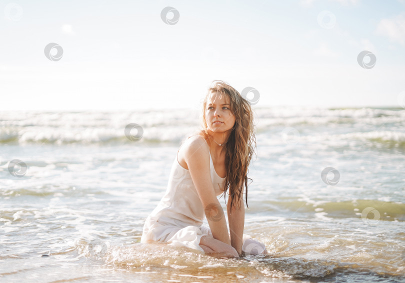 Скачать Молодая красивая блондинка с длинными волосами в белом платье наслаждается жизнью на морском пляже фотосток Ozero