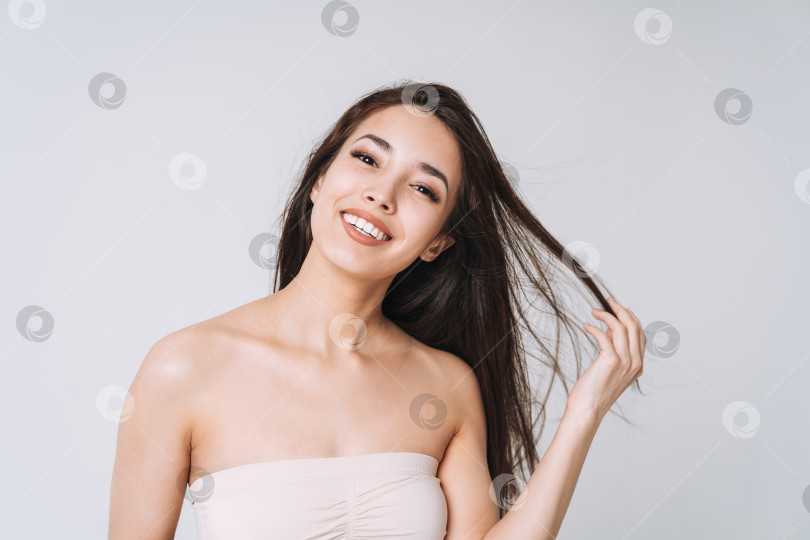 Скачать Красивый портрет счастливой молодой красивой азиатской женщины со здоровыми темными длинными волосами в верхней бандо на белом фоне изолированно фотосток Ozero