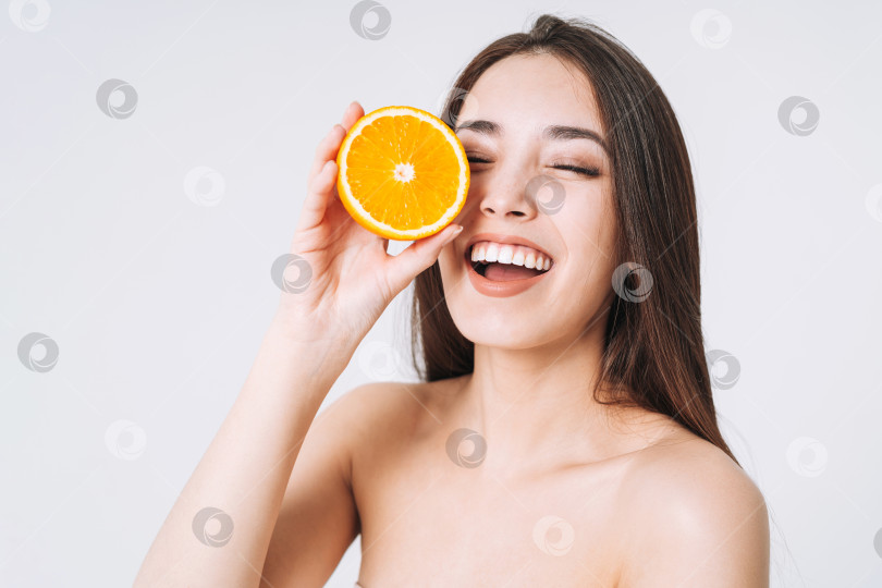 Скачать Красивый забавный портрет счастливой улыбающейся азиатской женщины с темными длинными волосами и апельсинами в руках на белом фоне изолированно фотосток Ozero
