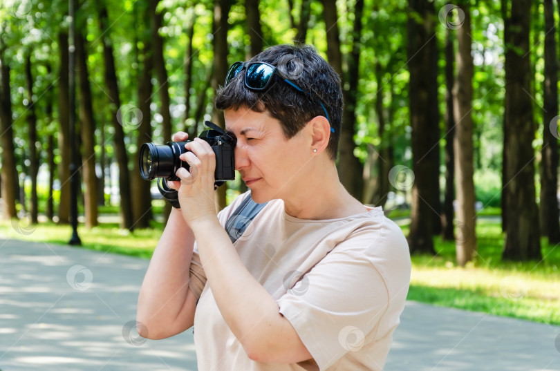 Скачать женщина фотографирует на камеру в городском парке. Фотограф-турист со своей камерой в парке фотосток Ozero