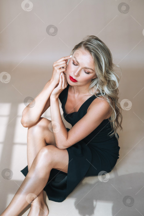 Скачать Портрет великолепной красивой молодой женщины-блондинки с ярким макияжем в вечернем платье на бежевом фоне фотосток Ozero