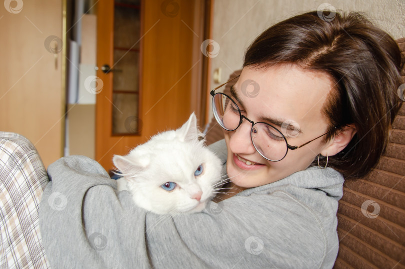 Скачать Симпатичная молодая женщина держит на руках белую кошку. фотосток Ozero