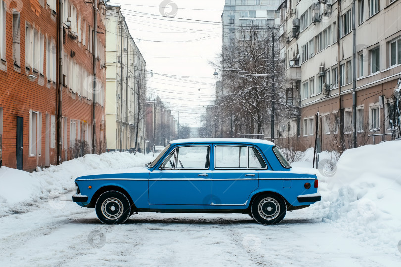 Скачать Старинный синий автомобиль, припаркованный зимой на заснеженной улице между многоквартирными домами. Старый автомобиль. Городская сцена, демонстрирующая классический автомобиль и холодные погодные условия фотосток Ozero