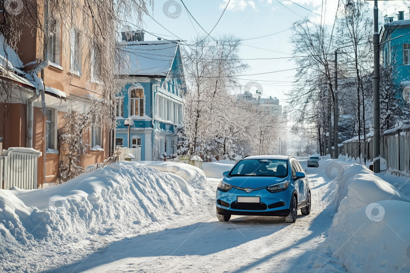 Скачать Синий компактный автомобиль едет по узкой заснеженной жилой улице, вдоль которой в лучах зимнего солнца выстроились разноцветные дома и заснеженные деревья. Концепция городского квартала на зимний сезон фотосток Ozero