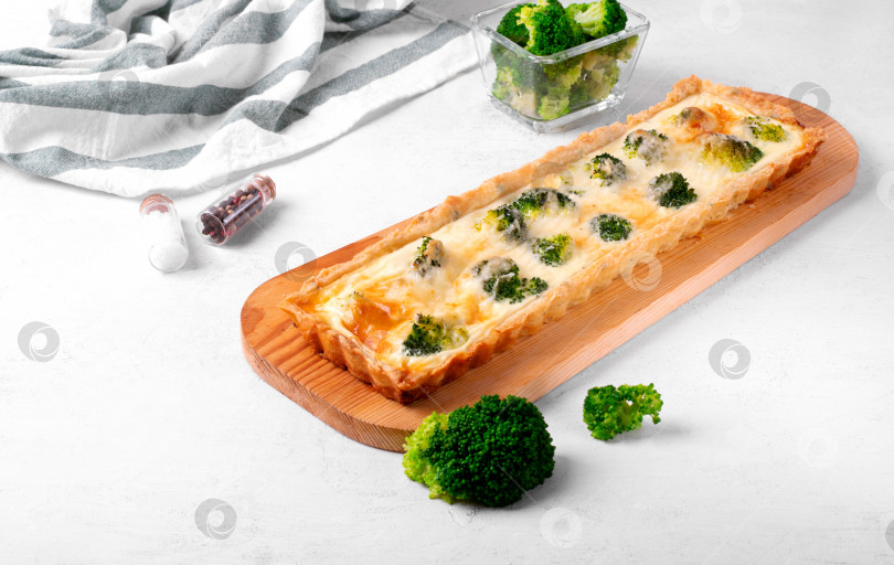 Скачать Пирог с брокколи и сыром прямоугольной формы на песочном тесте на белом столе. фотосток Ozero