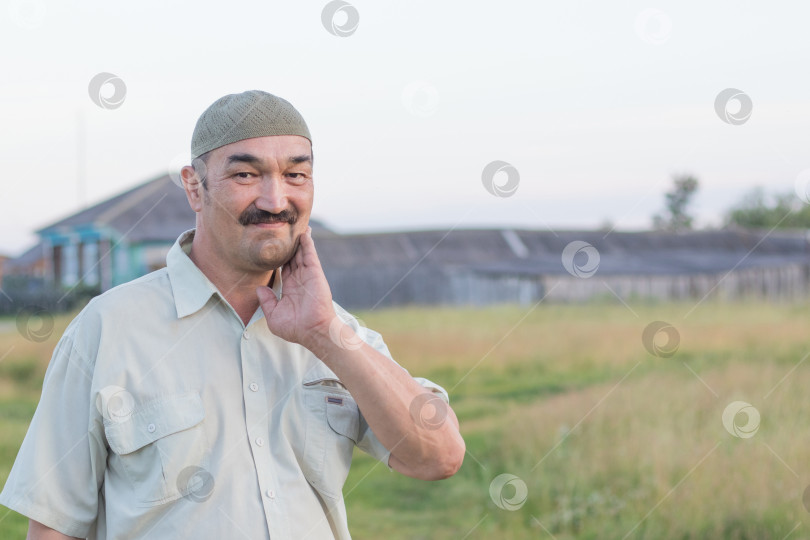 Скачать Портрет мужчины-мусульманина на фоне сибирской деревни, Россия фотосток Ozero