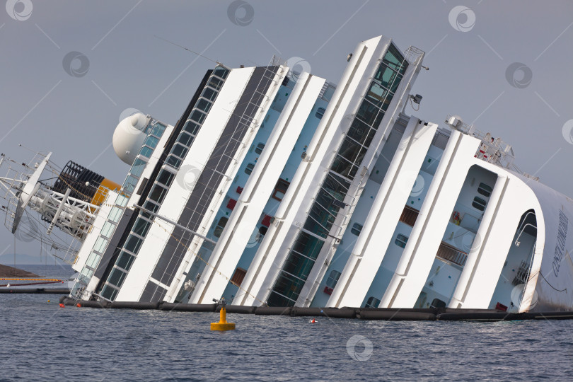 Скачать ДЖИЛЬО, ИТАЛИЯ - 28 апреля 2012 г.: Круизный лайнер Costa Concordia у побережья итальянского острова Джильо после кораблекрушения, произошедшего 13 января 2012 г. фотосток Ozero
