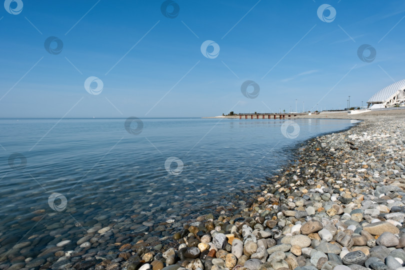 Скачать Спокойные воды вдоль галечного пляжа под ясным голубым небом в прибрежной зоне в солнечный день фотосток Ozero