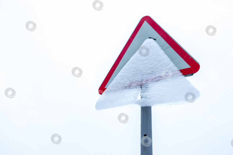 Скачать Дорожный знак, занесенный снегом. Ледяная корка скрывает символ на дорожном знаке. Белый фон фотосток Ozero