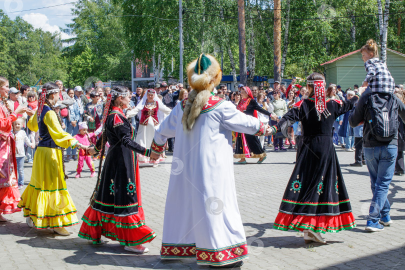 Скачать . Люди держатся за руки, танцуют в кругу. Ежегодный национальный праздник татар и башкир Сабантуй в городском парке. фотосток Ozero