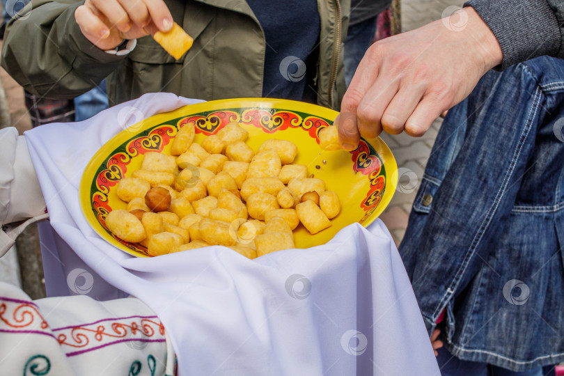 Скачать Восточная кухня. На руках у человека башкирский баурсак в тарелке с этническим рисунком. Вид сверху. фотосток Ozero