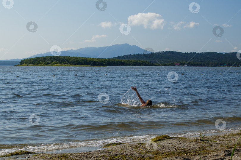 Скачать Девушка плавает в живописном озере, разбрызгивая воду. фотосток Ozero