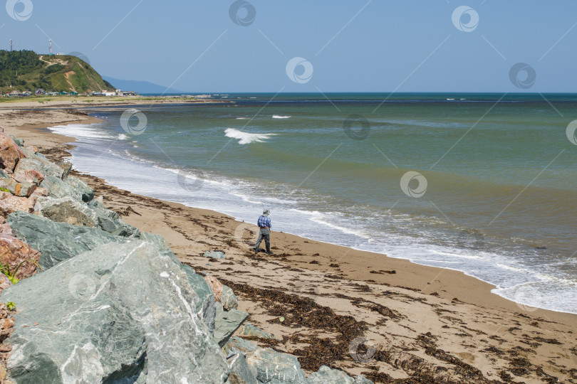 Скачать Рыбак ловит рыбу с удочкой на берегу моря недалеко от поселка Охотск. фотосток Ozero