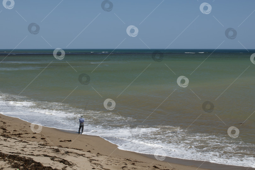 Скачать Рыбак ловит рыбу на берегу моря фотосток Ozero