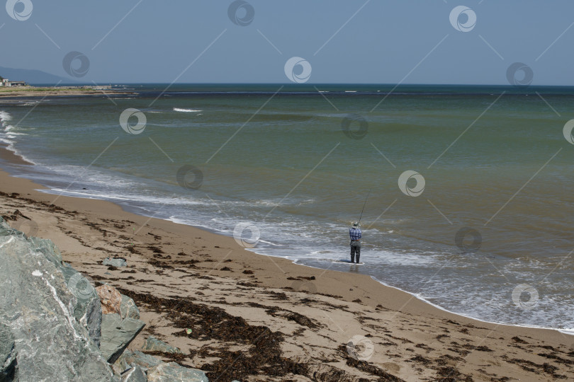 Скачать Рыбак ловит рыбу с удочкой на берегу моря недалеко от поселка Охотск. фотосток Ozero