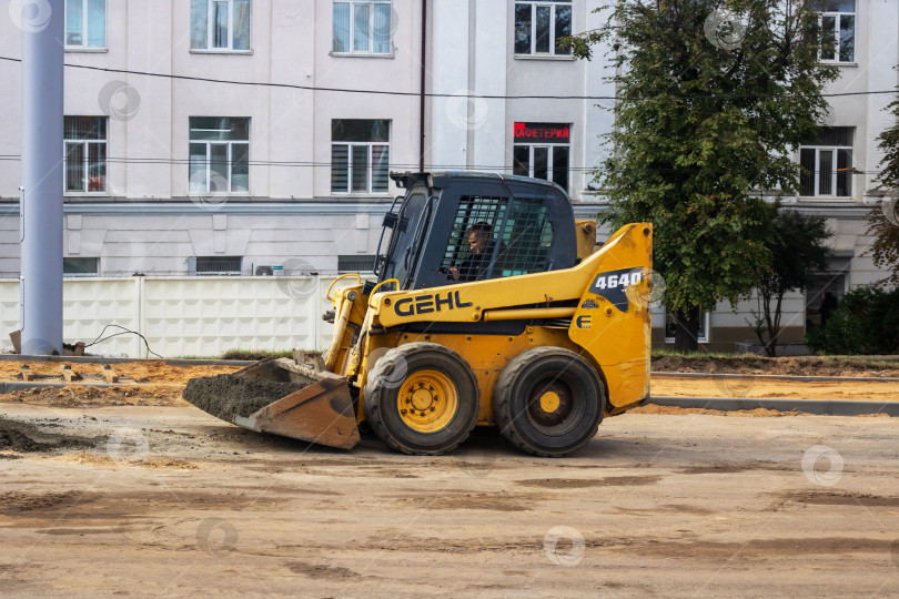 Скачать Беларусь, Минск - 06 октября 2023 года: Сегодня по грунтовой дороге едет ярко-желтый трактор gehl фотосток Ozero