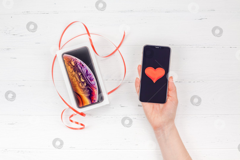 Скачать Женская рука с коробкой Apple iPhone XS и смартфоном фотосток Ozero