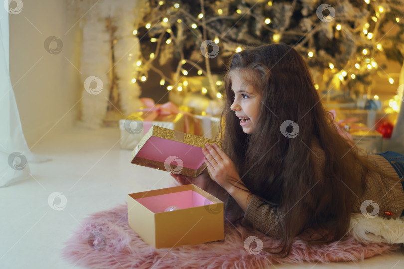Скачать Маленькая девочка распаковывает рождественские подарки фотосток Ozero