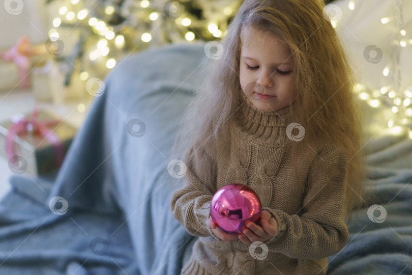 Скачать Маленькая девочка с рождественской игрушкой. фотосток Ozero